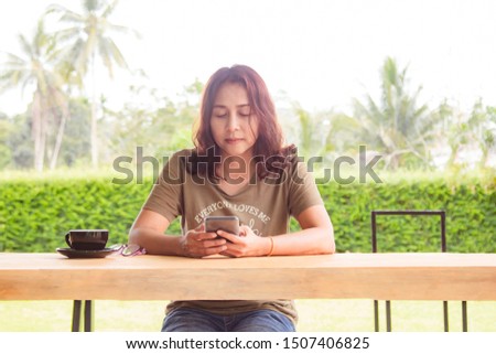 Woman's hands holding black mobile phone with blank screen on table and coffee cup in cafe