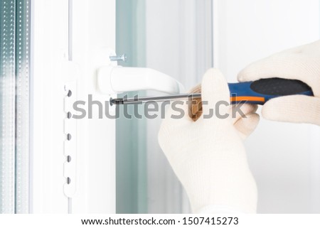 the hands of a worker fasten the handle to a plastic window, closeup view from the side Royalty-Free Stock Photo #1507415273