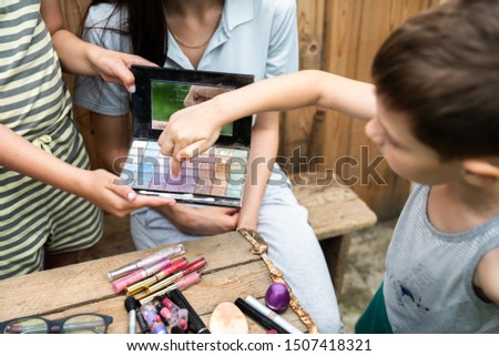 Little boy in casual clothes wonders how the sisters do makeup. Children spending time together outdoor in the village, summer holidays time