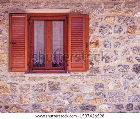 natural wood window frame with shutters on stonewall, space for text