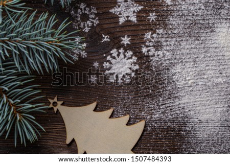 on a wooden Board with a green branch of spruce, toy , silhouette fir plywood and white snowflakes