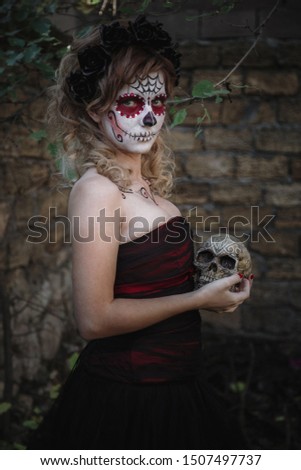 Closeup portrait of Calavera Catrina. Young woman with sugar skull makeup. Dia de los muertos. Day of The Dead. Halloween. in the forest with skull