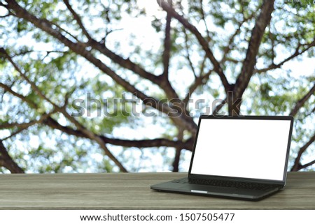 Space for text,Laptop on the wooden desk on background blur of tree,blank screen for graphics display montage.- Image