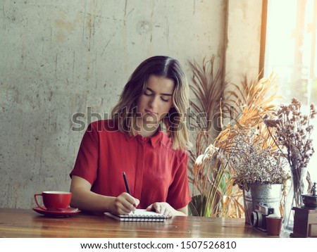 Beautiful woman writing for idea with her work in coffee shop, lifestyle