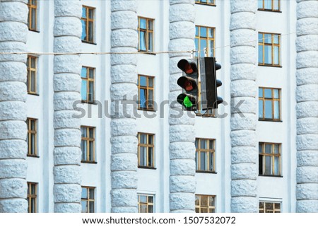 Green traffic lights against big administrative building