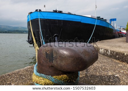 Big blue ship or tanker anchored to an iron dock cleat, in Veliko Gradiste, Serbia, on Danube river on the border with Romania