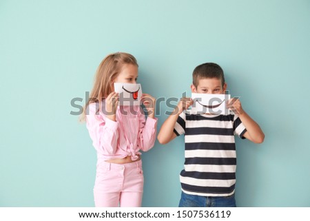 Little children hiding mouths behind drawn smiles on color background