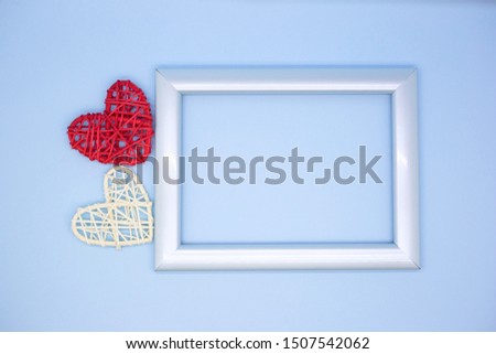 Blue photo frame on a blue background next to red and white wooden hearts. Valentine's day greeting card. Love concept. Place for text