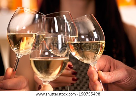 Clinking glasses with white wine and toasting. Royalty-Free Stock Photo #150755498