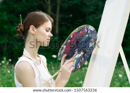woman draws an easel painting oil paints