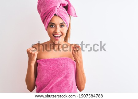 Young beautiful woman wearing shower towel after bath over isolated white background celebrating surprised and amazed for success with arms raised and open eyes. Winner concept.