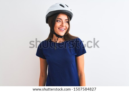 Young beautiful cyclist woman wearing security bike helmet over isolated white background looking away to side with smile on face, natural expression. Laughing confident.