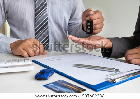 Car dealership provides advice about insurance details and car rental information and delivers the keys after signing the rental contract.