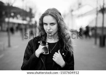 sad serious blond woman in leather coat looking at camera, monochrome