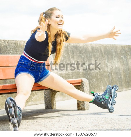 Happy joyful young woman wearing roller skates relaxing after long ride. Girl having fun during summer time.