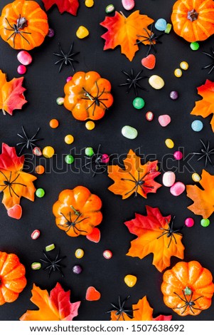 Bright Halloween composition with sweets and pumpkins on black background top view pattern