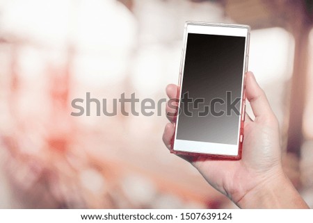 Smartphone in hand with bokeh background and black empty screen.