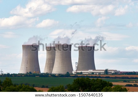 View of cooling chimneys of nuclear power plant. Landscape with forest and trees, green lawn under blue sky with clouds and smoke. Royalty-Free Stock Photo #1507640135