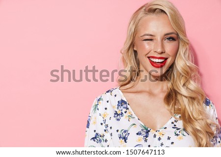 Image of gorgeous woman with long blond hair smiling and winking at camera isolated over pink background Royalty-Free Stock Photo #1507647113