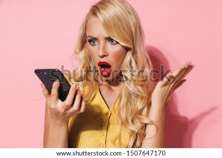 Image of irritated woman with long blond hair expressing outrage while holding cellphone isolated over pink background