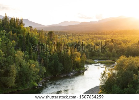 The sun setting over a river in a   mountain wilderness.  Jamtland, Sweden. Royalty-Free Stock Photo #1507654259