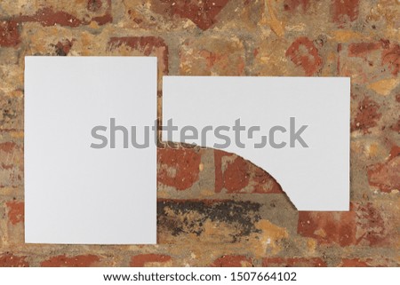 Blank white rectangular and torn rectangular pictures on a brick wall