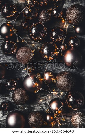 Christmas or New Year background. Vintage Christmas tree toy decoration balls and light garland over rustic wooden background, selective focus, copy space