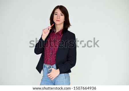 Portrait of a pretty asian brunette girl with black hair in a dark jacket and blue jeans on a white background. It stands right in front of the camera, with emotions in various poses.