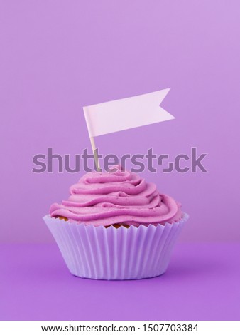 Single blueberry cupcake on a table with a festive empty flag on top, vertical image