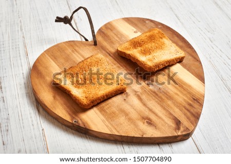 Toasted white bread toast on a wooden background in the shape of a heart.
