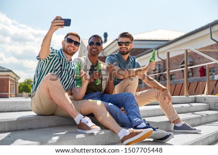 leisure, technology and people concept - happy male friends taking selfie by smartphone and drinking beer on street in summer