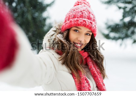 christmas, season and people concept - happy smiling woman taking selfie outdoors in winter park