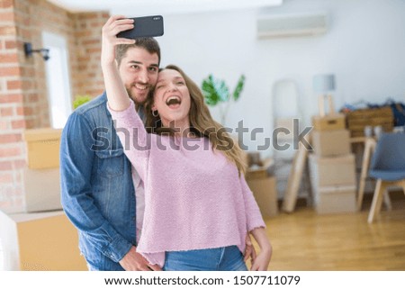 Young beautiful couple taking a selfie photo using smartphone smiling very happy for moving to a new home