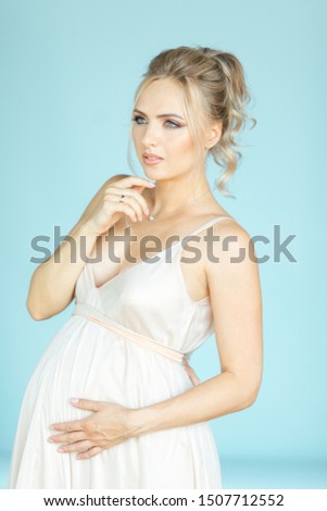 pregnant photo shoot indoor. pregnant bride with flowers. beautiful young blond woman expecting baby. girl on 30 week. nine month term of pregnancy. gorgeous mother to be. surprised pregnancy. wedding