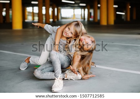 Two beautiful girls skateboarding, having fun and playing in the parking lot. 