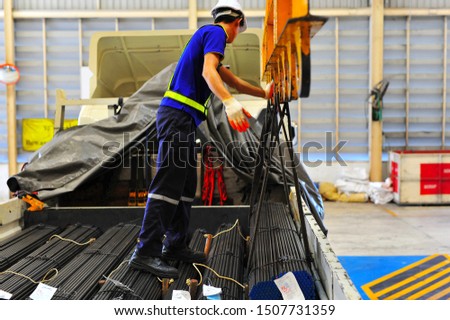The round steel bar discharging from electric crane hook and load onto the truck by truck driver. Royalty-Free Stock Photo #1507731359