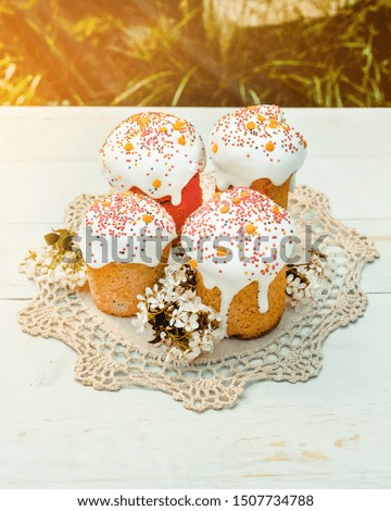 Happy Easter cake with sprinkles on glaze. Cake on light green rustic board, lace cloth, blur green plants and sun. Homemade bakery, spring holiday preparation. Selective focus, free text space. 