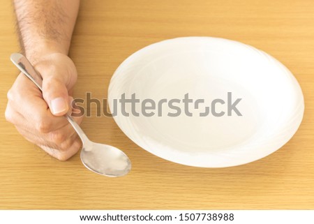 Male hand with spoon and white dish