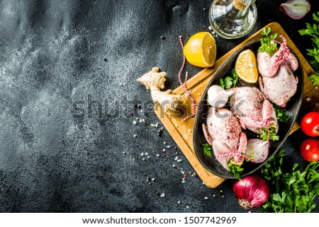 Cooking healthy diet lunch concept. Three whole quails with spices, herbs, vegetables, olive oil, for cooking on a black stone concrete table copy space
