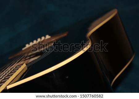 Black guitar on blue background close-up. Guitar neck and strings.