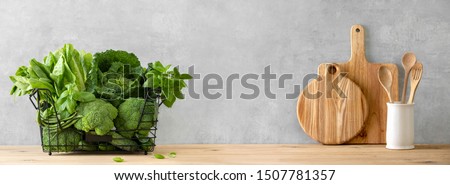 Healthy food cooking concept, front view on fresh green leafy vegetables and kitchen utensils standing on wooden countertop, composition with blank space Royalty-Free Stock Photo #1507781357