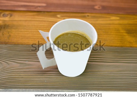 Picture of hot coffee in a paper cup on the table.