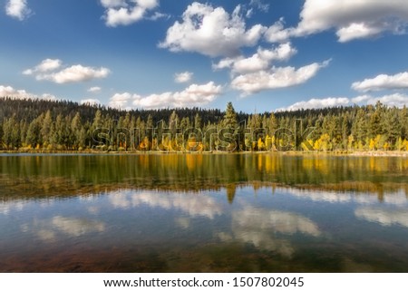 Pristine view of a mirror lake on a crisp autumn day with mountains and fall foliage.