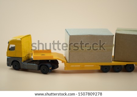 Miniature cardboard box on yellow tow truck. Delivery of the order from the online store