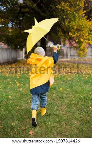 Boys are walking in the autumn park. Autumn style. Children in a raincoat, rubber boots, with an umbrella. walk under the rain. Damp weather. boy runs with a yellow umbrella.umbrella with ears