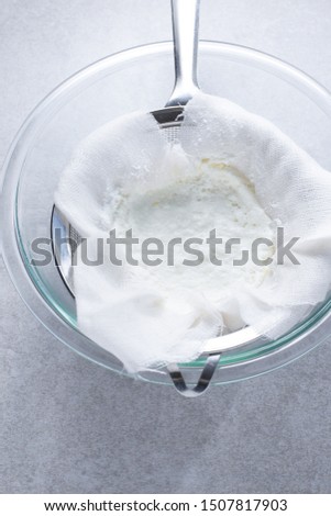 Just made fresh ricotta draining in cheesecloth and strainer over a glass bowl. Royalty-Free Stock Photo #1507817903