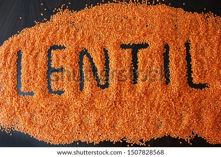 written lentils in orange small natural groats on a dark a background