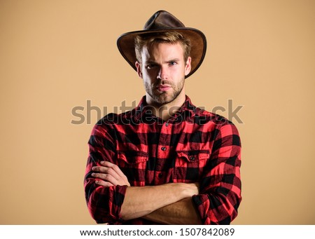 American cowboy. Beauty standard. Example of true masculinity. Cowboy wearing hat. Western life. Man unshaven cowboy beige background. Unshaven guy in cowboy hat. Handsome bearded macho.