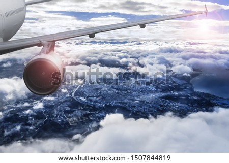 Jet Airplane Flying High in the Sky Above a Big City, View with Wing and Engine