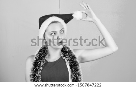 Woman with tinsel celebrate winter holiday christmas party. Woman in christmas santa hat play with pompon pink and blue background. Christmas attribute concept. Girl cheerful face celebrate christmas.